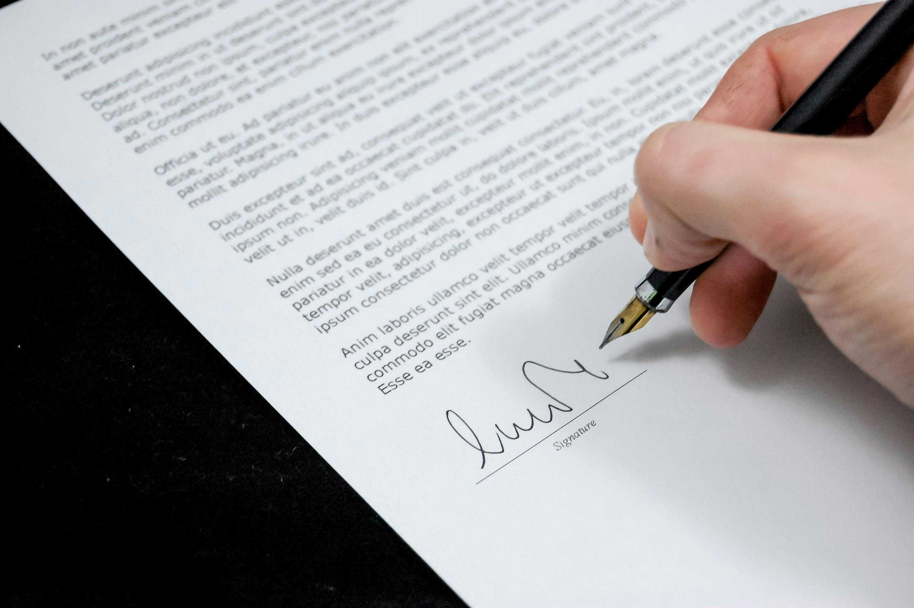 Foto van een hand die een brief ondertekend